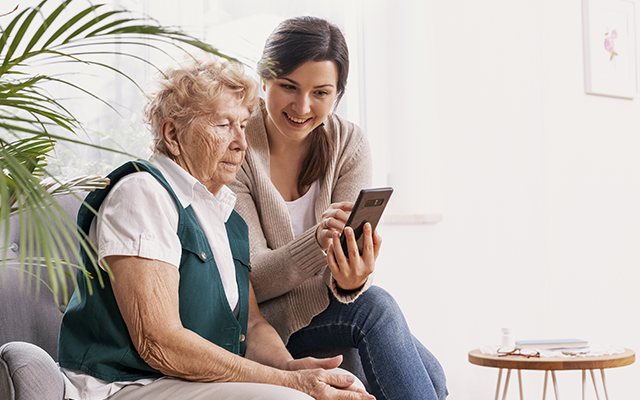 Elderly woman with younger woman looking at mobile phone
