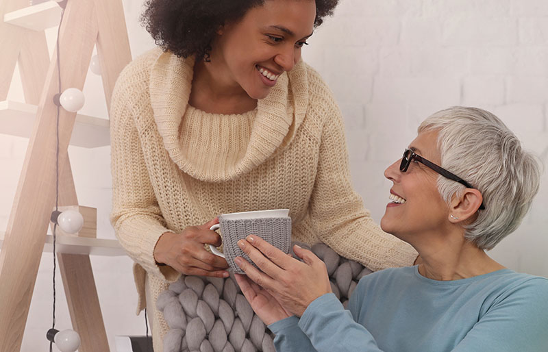 Live-in carer giving cup of tea to elderly lady