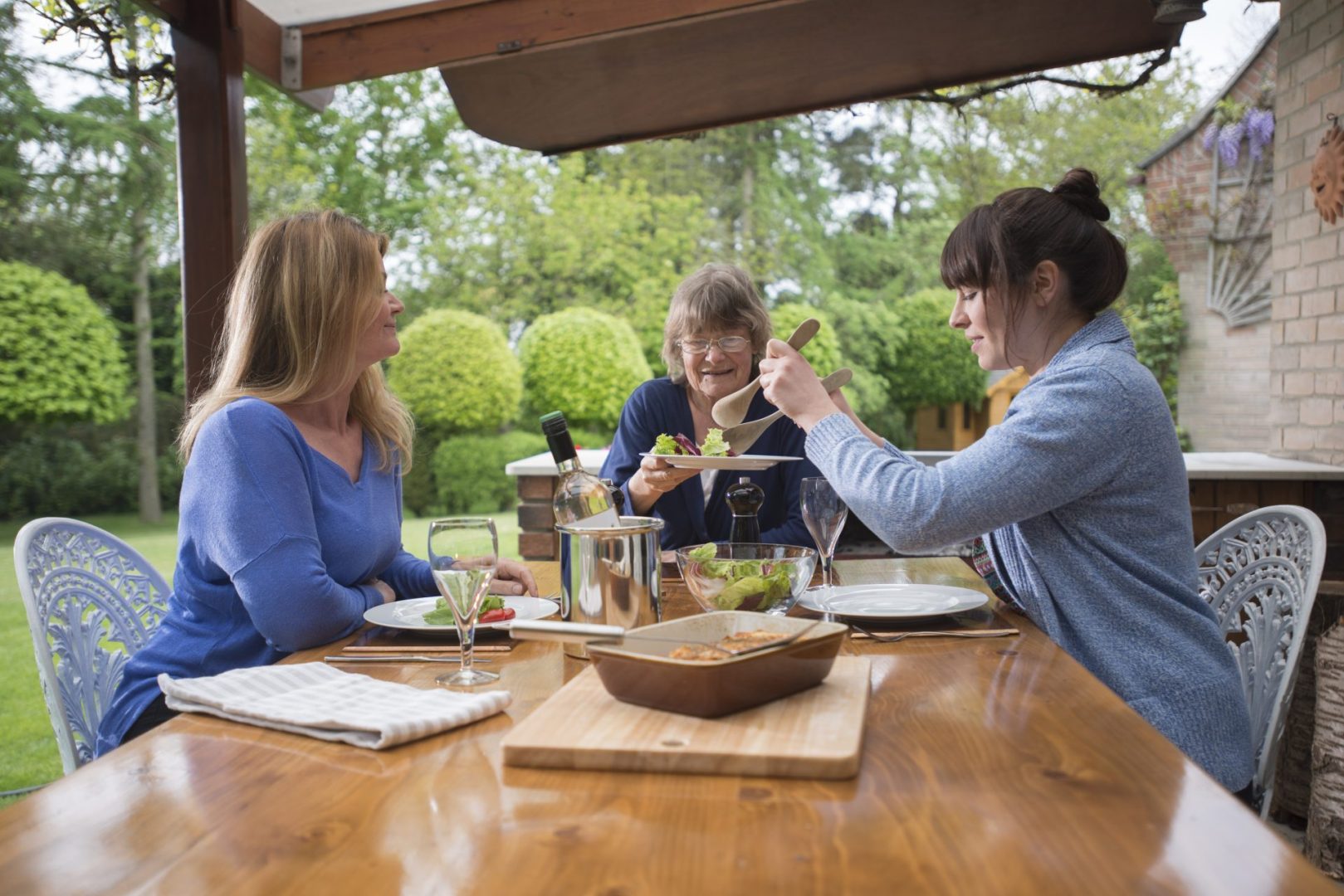 mother, adult daughter, and carer having dinner outside