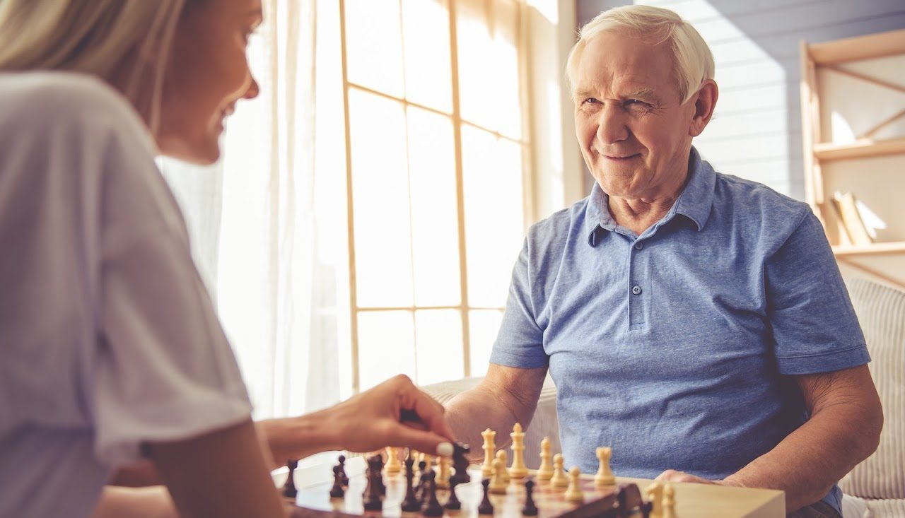 Live-in companion carer playing chess with patient