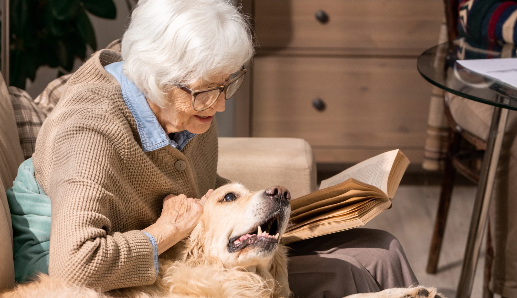 Client cuddling her dog and reading a book in her living room